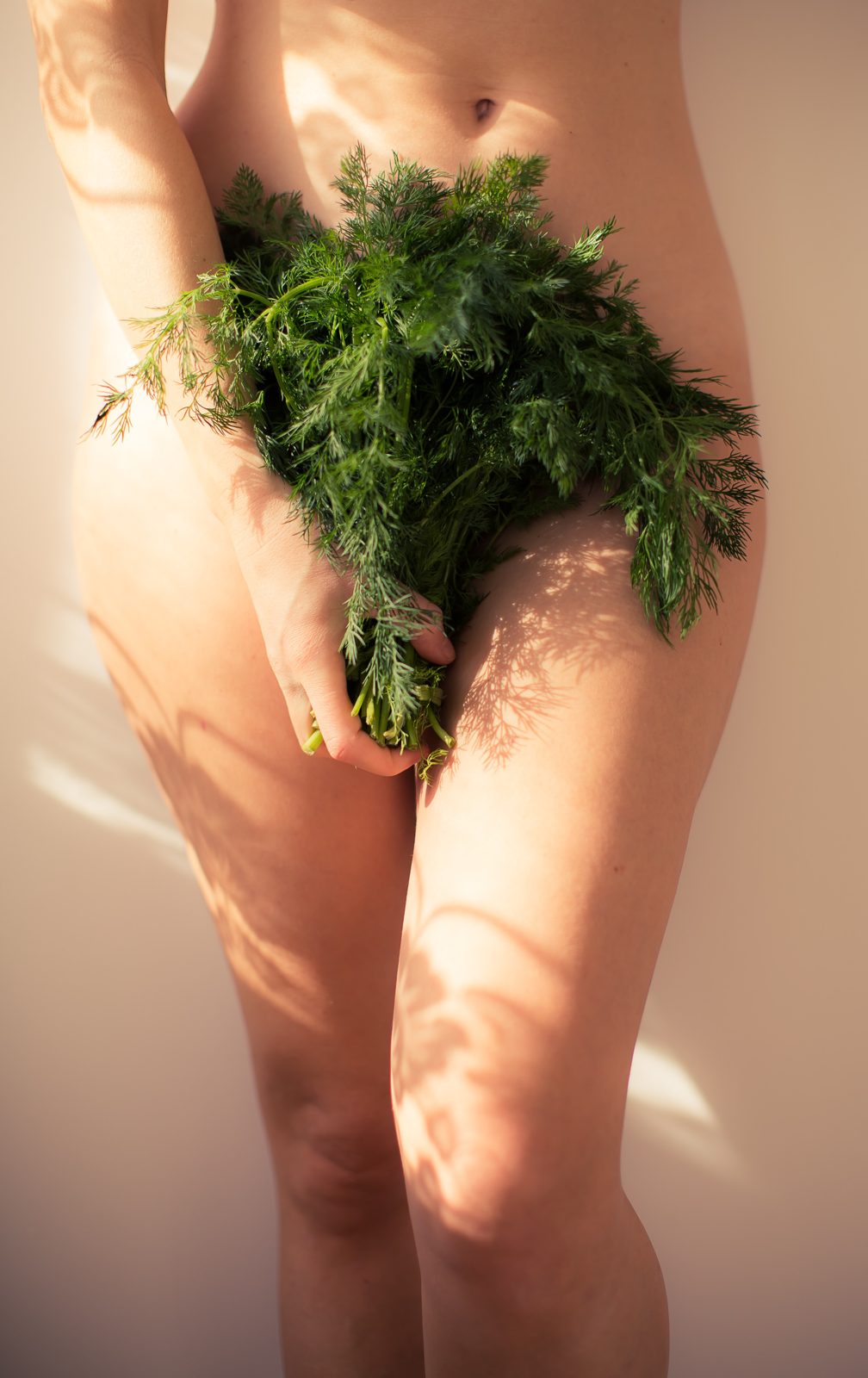 A woman holding a bunch of fresh green herbs in front of her body